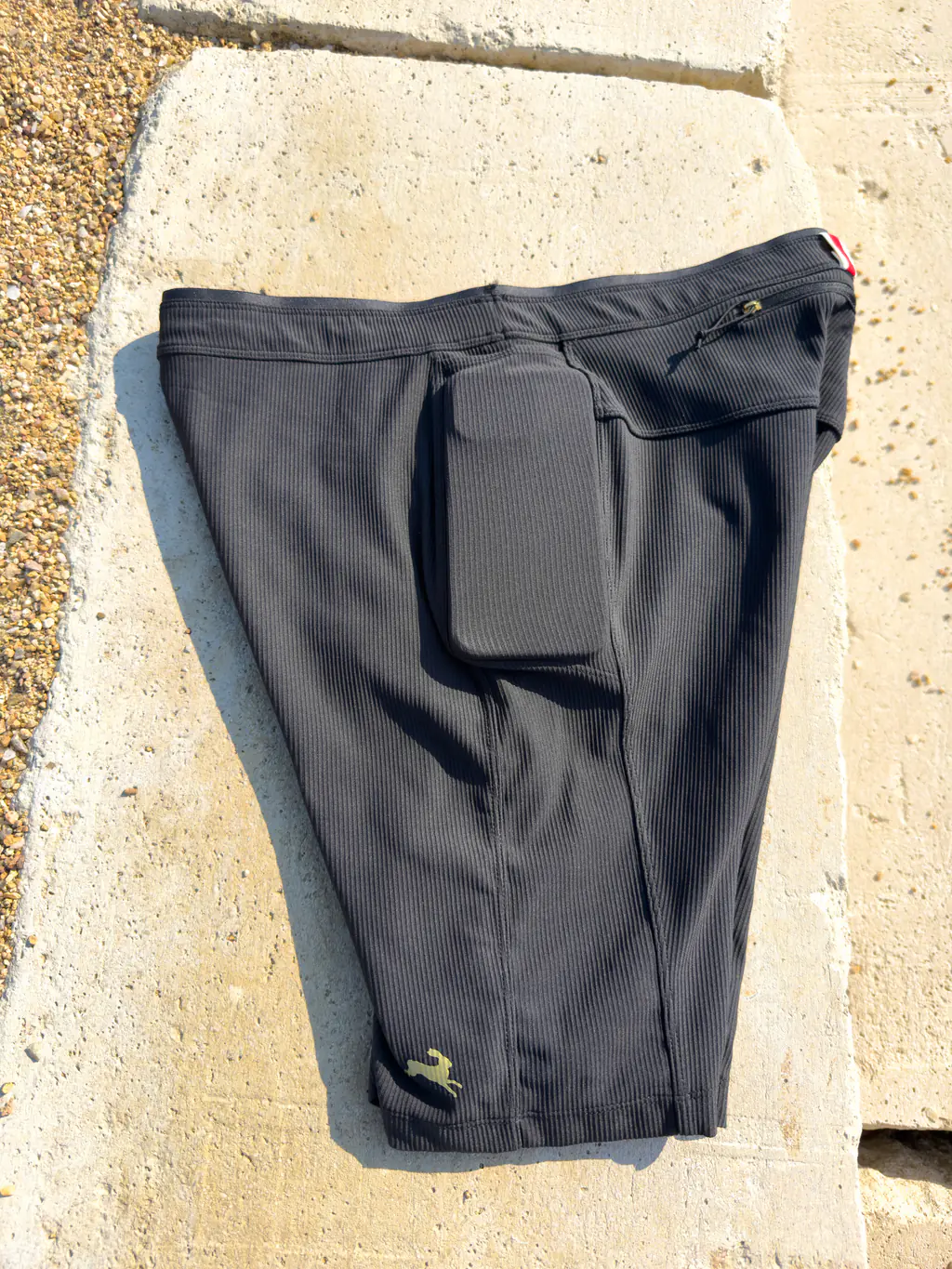 A side view of the half tights with an iPhone 12 Pro Max case in the drop-in side pocket, showing a tight fit. A side view of the half tights with an iPhone 12 Pro Max case in the drop-in side pocket, showing a tight fit.