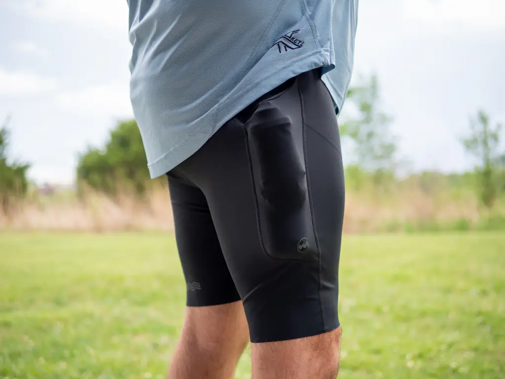 A side-view of a runner wearing the half tights, with the side pockets loaded with both a 500ml soft flask and a 150ml nutrition flask, which bulges quite a bit. A side-view of a runner wearing the half tights, with the side pockets loaded with both a 500ml soft flask and a 150ml nutrition flask, which bulges quite a bit.