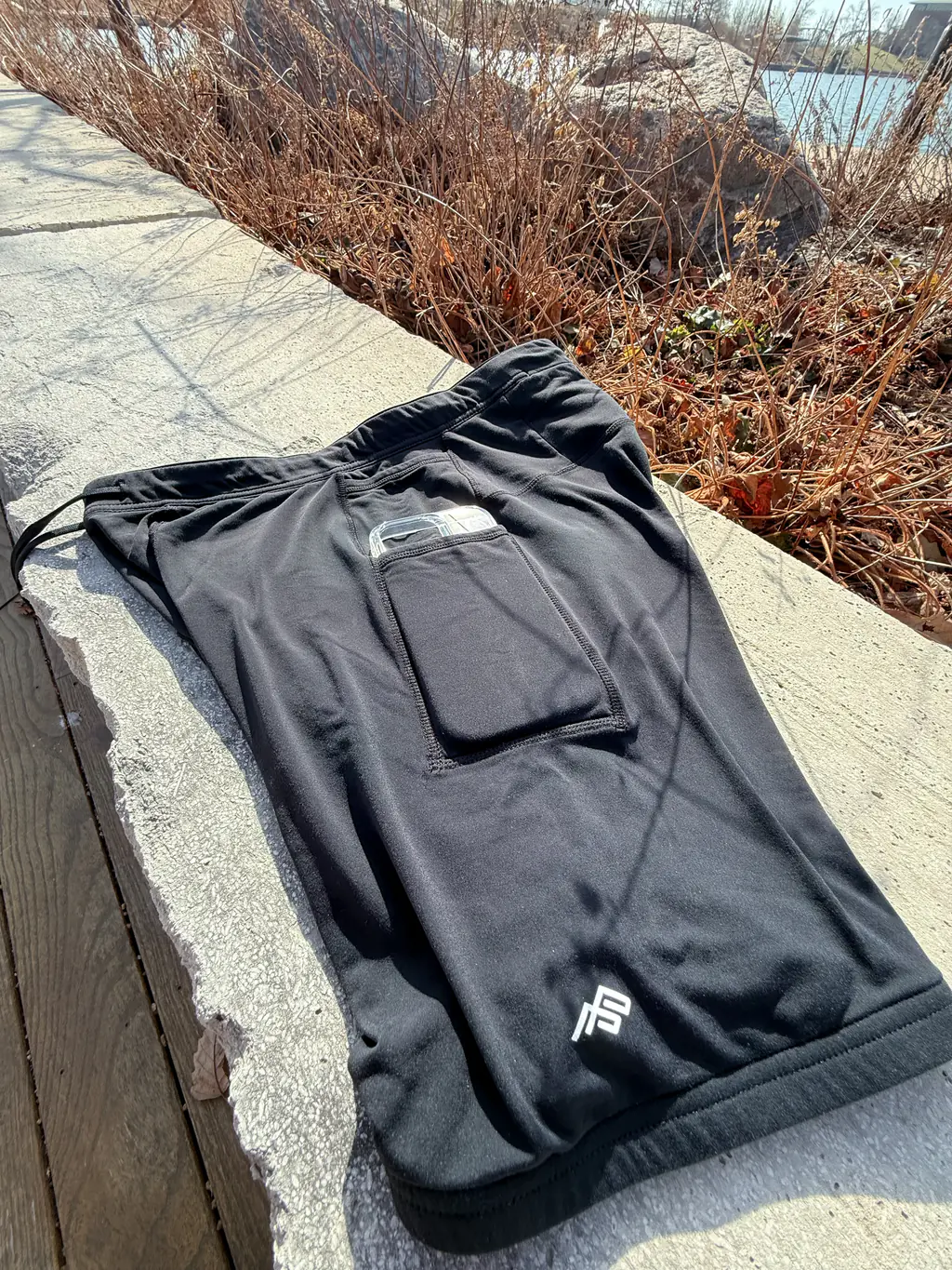 An overall side view of the half tights, showing the dual pocket system, with an iPhone 16 Pro case in the larger bottom pocket An overall side view of the half tights, showing the dual pocket system, with an iPhone 16 Pro case in the larger bottom pocket
