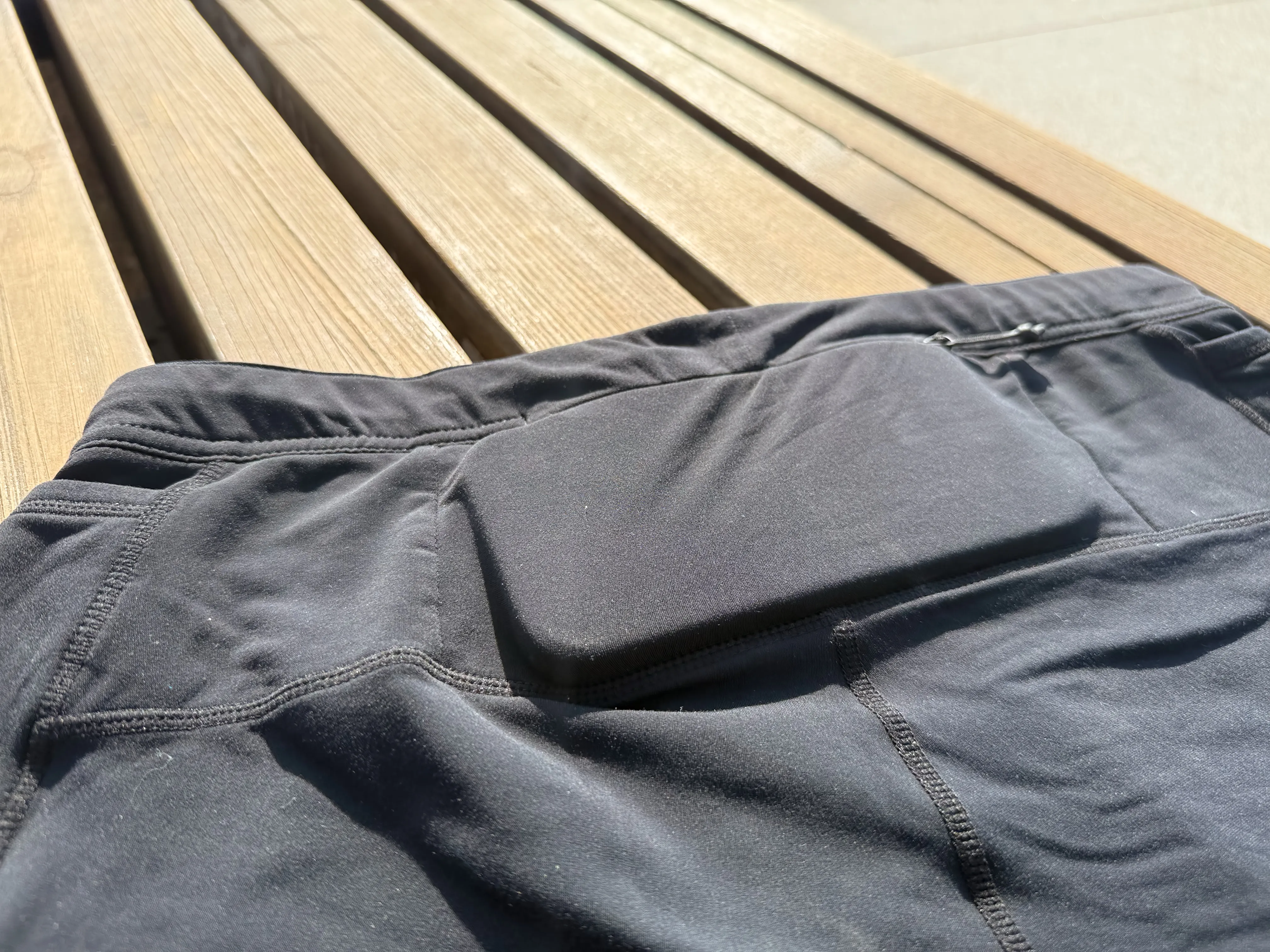 A closeup of the rear zippered pocket with an iPhone 16 Pro case in it, showing how the phone takes up most of the pocket, but does still zip closed