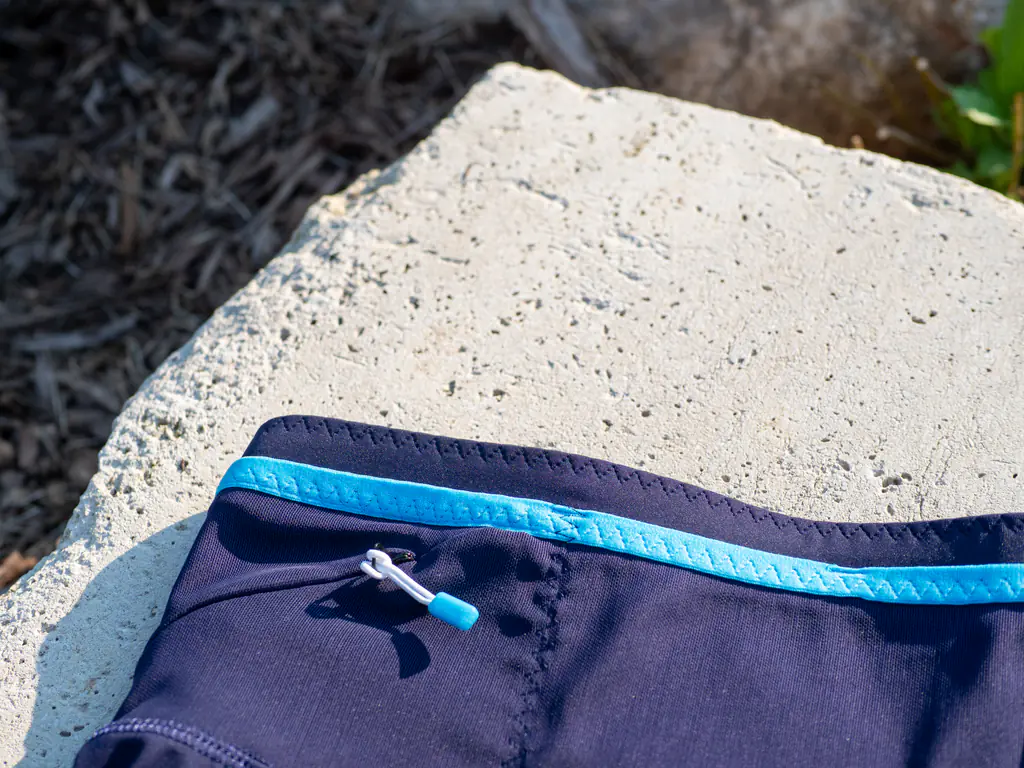 A closeup of the zipper pull, with the blue elastic top band running above it